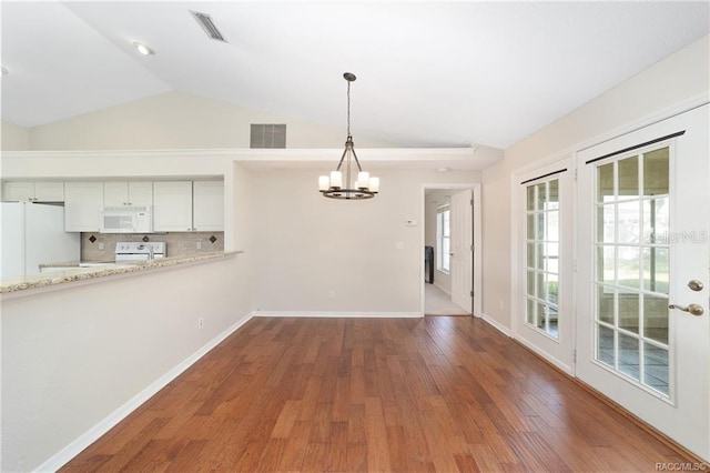 unfurnished dining area with a chandelier, hardwood / wood-style floors, and vaulted ceiling