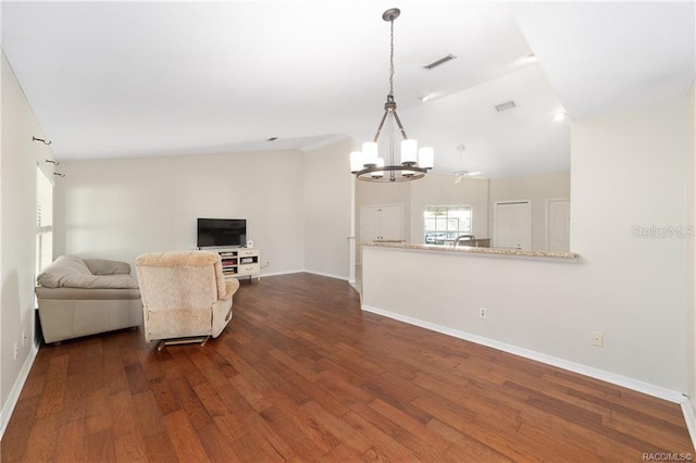 living room featuring an inviting chandelier, dark hardwood / wood-style floors, and vaulted ceiling