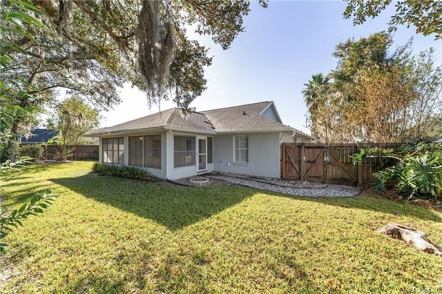 rear view of property featuring a sunroom and a yard