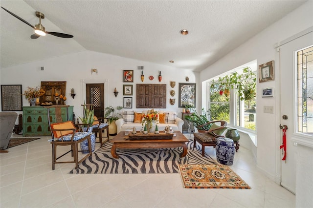 living room featuring ceiling fan, light tile patterned floors, a textured ceiling, and vaulted ceiling