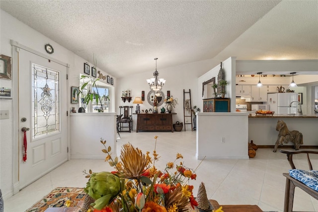 dining room with sink, vaulted ceiling, light tile patterned floors, a textured ceiling, and a chandelier