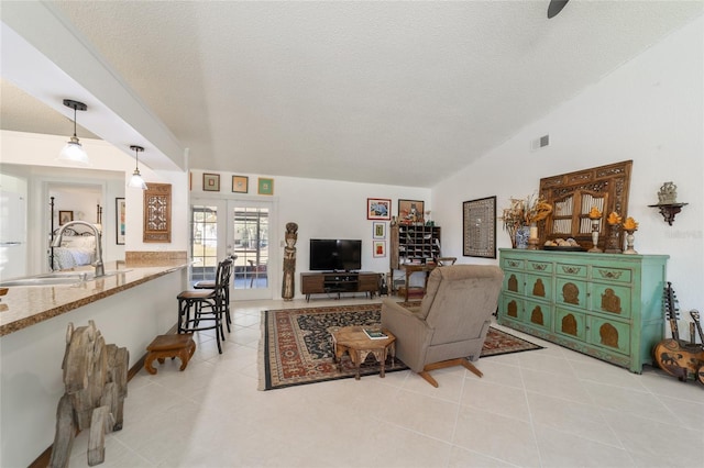 tiled living room featuring french doors, a textured ceiling, vaulted ceiling, and sink