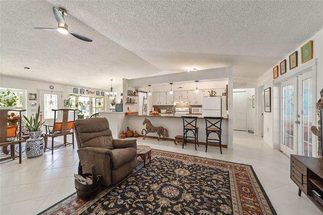 living room featuring ceiling fan with notable chandelier, french doors, and a textured ceiling