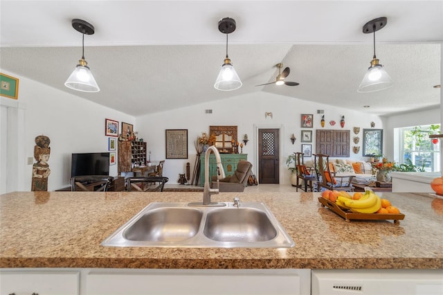 kitchen with vaulted ceiling, ceiling fan, sink, pendant lighting, and white cabinets