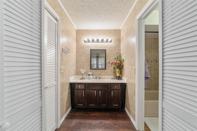 bathroom featuring vanity, a textured ceiling, crown molding, tile walls, and hardwood / wood-style floors