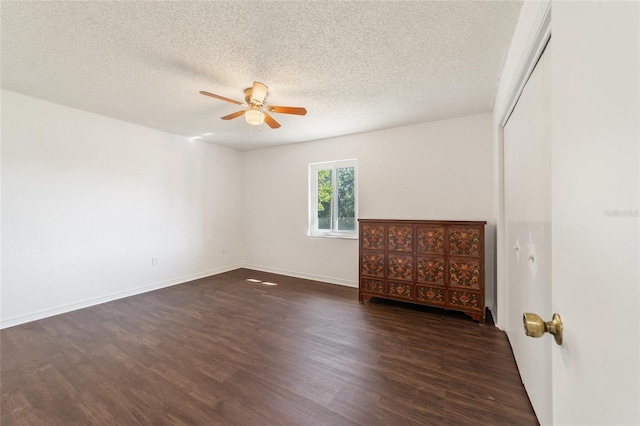 unfurnished room with ceiling fan, dark wood-type flooring, and a textured ceiling