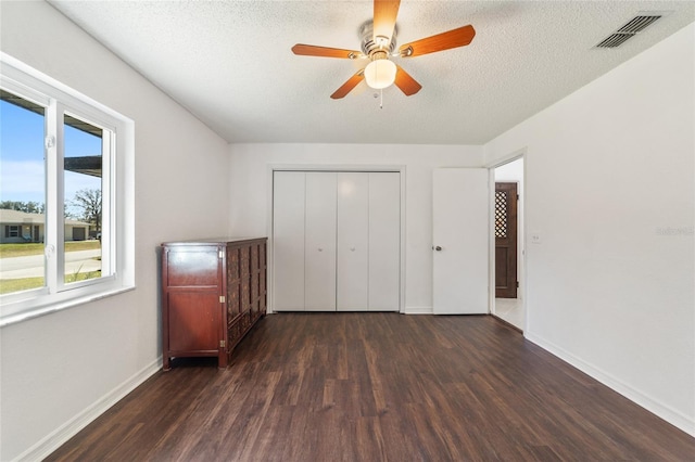 unfurnished bedroom featuring a textured ceiling, ceiling fan, dark wood-type flooring, and a closet