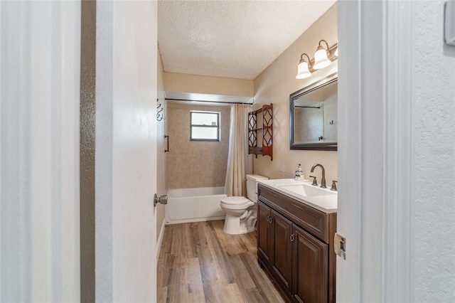 full bathroom featuring shower / bath combination with curtain, vanity, a textured ceiling, wood-type flooring, and toilet