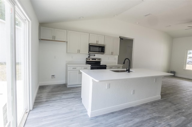 kitchen featuring a kitchen island with sink, sink, vaulted ceiling, a wealth of natural light, and stainless steel appliances