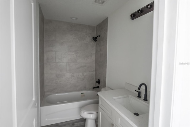 full bathroom featuring vanity, wood-type flooring, tiled shower / bath combo, and toilet