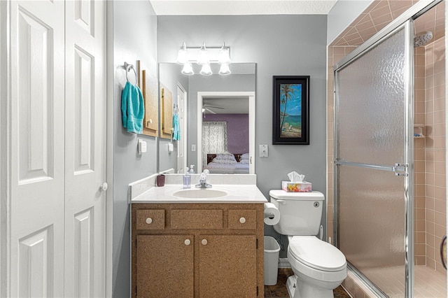 bathroom with vanity, toilet, an enclosed shower, and ceiling fan