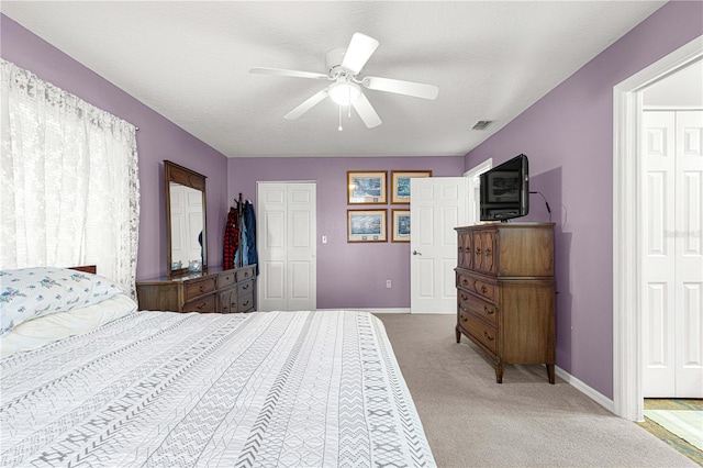 bedroom featuring light carpet, a textured ceiling, and ceiling fan