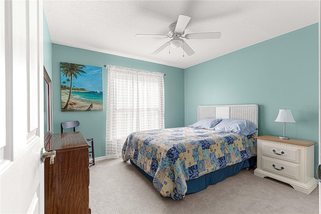 bedroom featuring ceiling fan, light carpet, and a textured ceiling