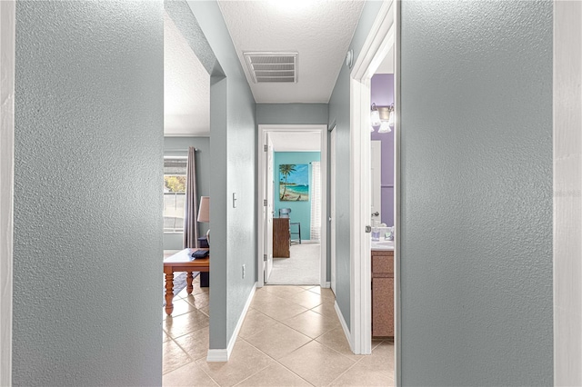 hallway featuring light tile patterned flooring and a textured ceiling