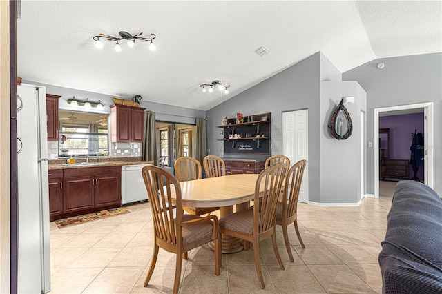 tiled dining area featuring a textured ceiling, lofted ceiling, and sink