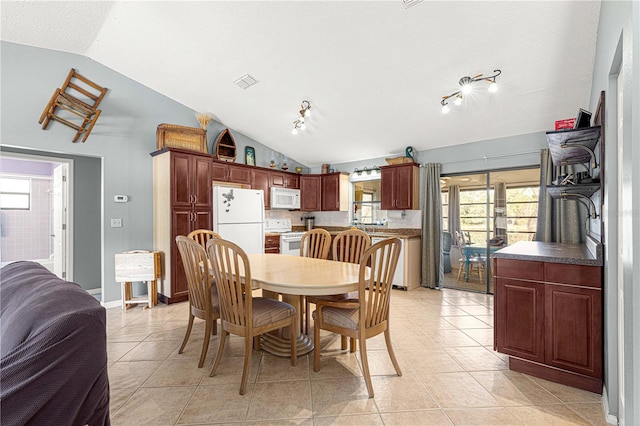 tiled dining area with a textured ceiling, rail lighting, and vaulted ceiling