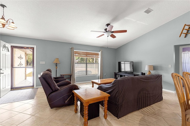 tiled living room with ceiling fan with notable chandelier, lofted ceiling, and a textured ceiling