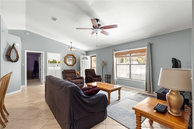 tiled living room featuring lofted ceiling, ceiling fan, separate washer and dryer, and a textured ceiling