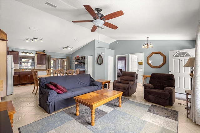 living room featuring ceiling fan with notable chandelier, light tile patterned flooring, lofted ceiling, and stacked washing maching and dryer