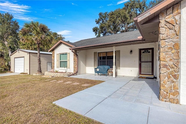 view of front of home with an outbuilding, covered porch, a front yard, and a garage