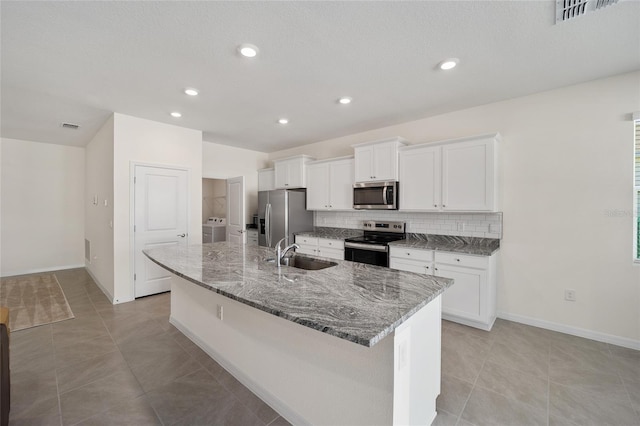 kitchen featuring appliances with stainless steel finishes, sink, white cabinets, washer / clothes dryer, and a large island