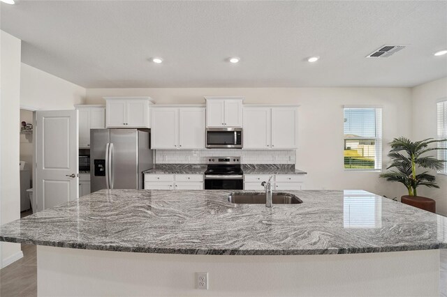 kitchen featuring appliances with stainless steel finishes, white cabinetry, a large island, and sink