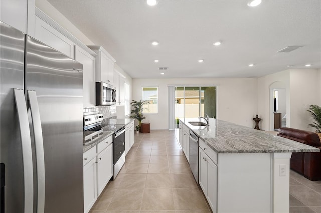 kitchen featuring sink, light stone countertops, an island with sink, white cabinetry, and stainless steel appliances