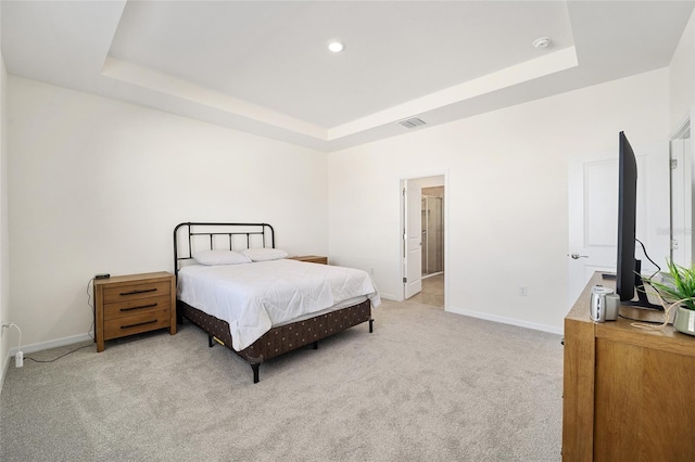 bedroom with a raised ceiling and light carpet