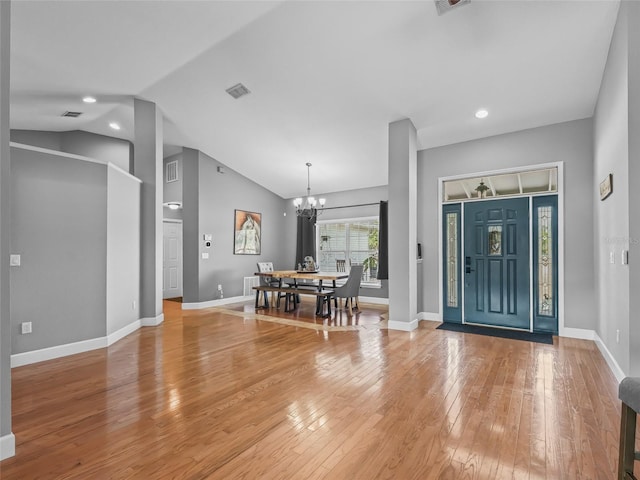 entrance foyer featuring lofted ceiling, light wood-type flooring, and an inviting chandelier