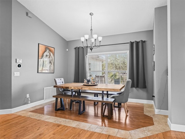 dining space featuring a chandelier, light hardwood / wood-style floors, and vaulted ceiling