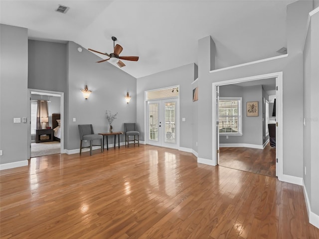 unfurnished living room featuring hardwood / wood-style flooring, ceiling fan, high vaulted ceiling, and french doors