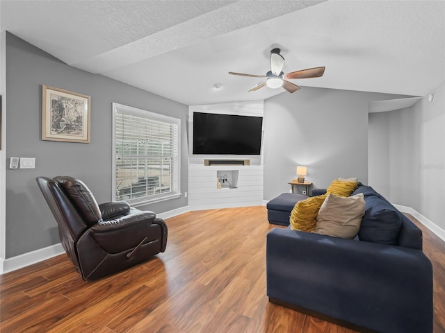 living room with a textured ceiling, ceiling fan, dark wood-type flooring, and vaulted ceiling