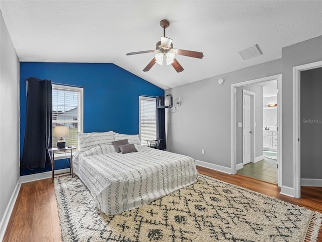 bedroom featuring hardwood / wood-style flooring, ceiling fan, lofted ceiling, and ensuite bath