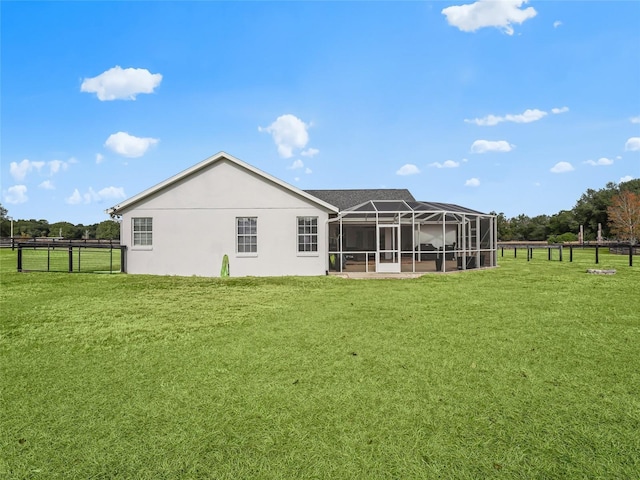 rear view of house featuring glass enclosure and a lawn