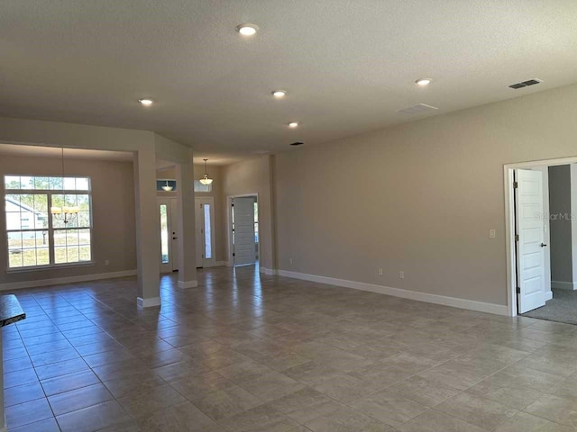 tiled empty room featuring a textured ceiling