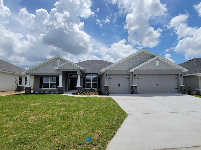 8309 SW 58th Ave, Ocala, FL 34476 - craftsman house featuring an attached garage, concrete driveway, a front lawn, stucco siding, and stone siding