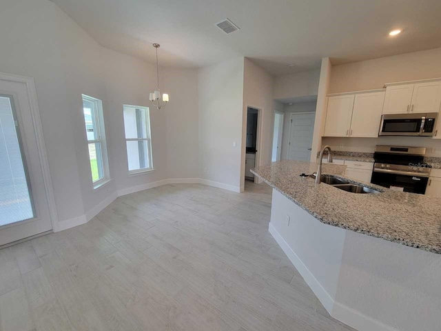 8309 SW 58th Ave, Ocala, FL 34476 - kitchen with appliances with stainless steel finishes, a chandelier, light stone countertops, white cabinets, and light wood-style flooring