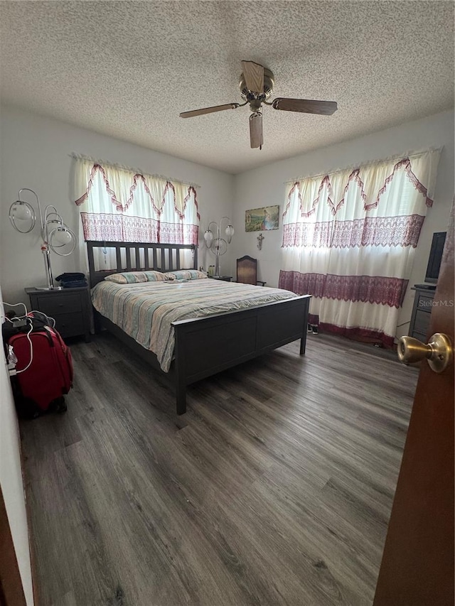 bedroom with ceiling fan, a textured ceiling, and dark hardwood / wood-style flooring