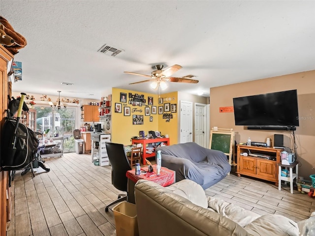 living room with ceiling fan, light hardwood / wood-style floors, and a textured ceiling