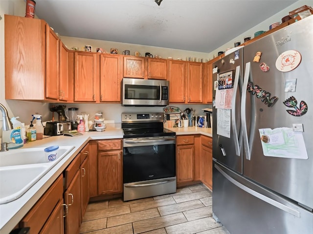 kitchen featuring light wood-type flooring, stainless steel appliances, and sink