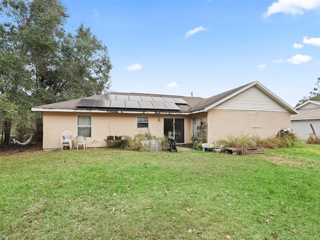 back of property featuring solar panels and a yard