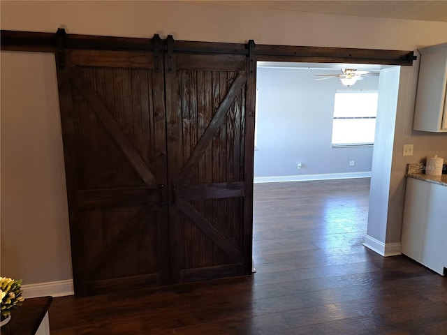 hall with a barn door and dark hardwood / wood-style floors