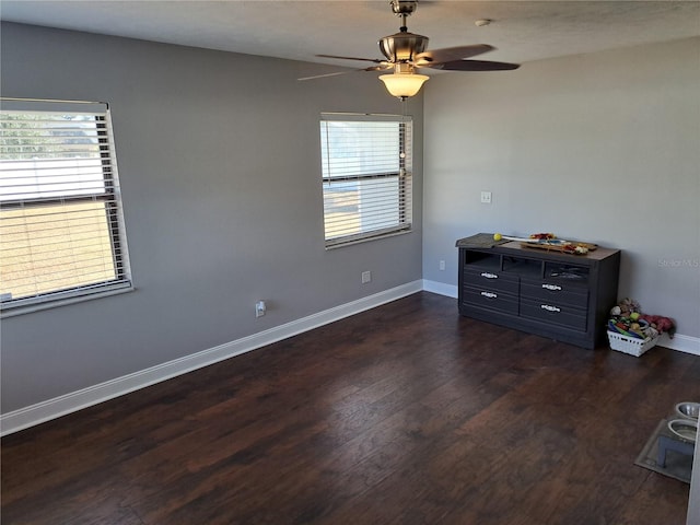 empty room with ceiling fan and dark hardwood / wood-style flooring