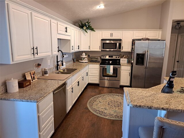 kitchen featuring white cabinets, lofted ceiling, sink, and appliances with stainless steel finishes