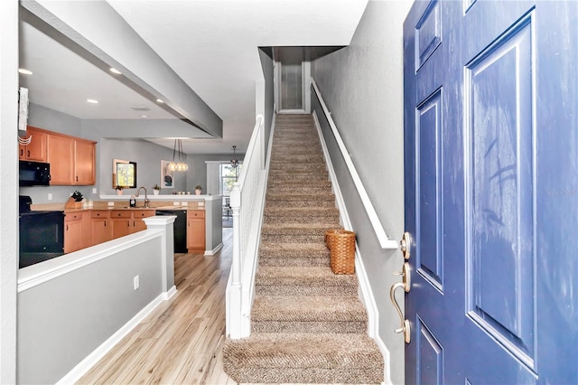 stairs with a chandelier, wood-type flooring, and sink