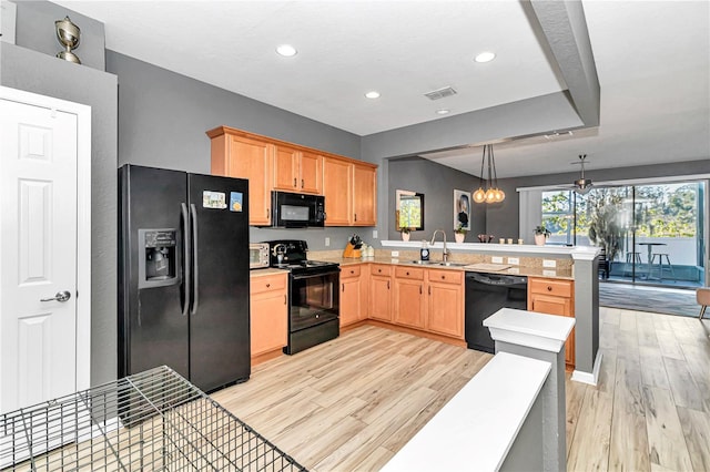 kitchen featuring black appliances, decorative light fixtures, light wood-type flooring, and kitchen peninsula