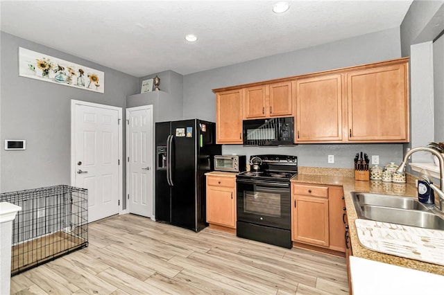 kitchen featuring a textured ceiling, sink, light hardwood / wood-style floors, and black appliances