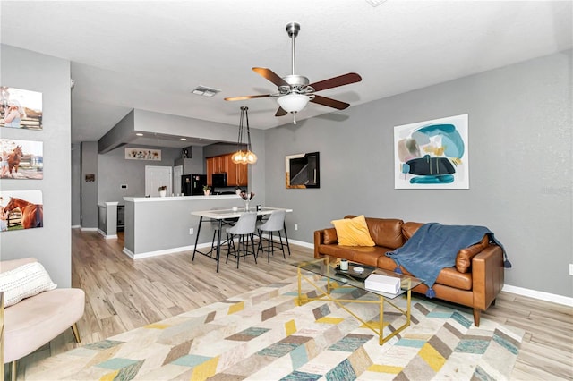 living room featuring light hardwood / wood-style flooring and ceiling fan