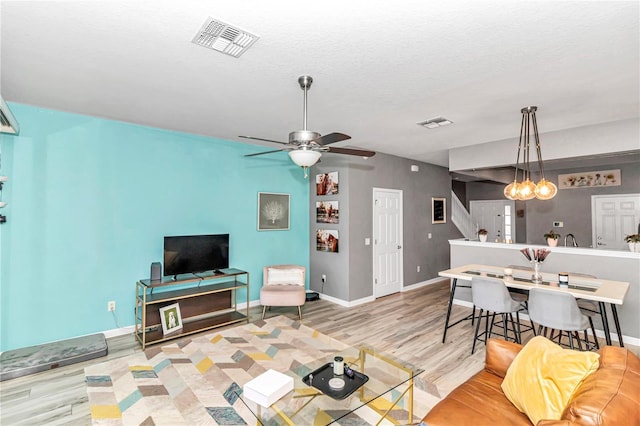 living room with a textured ceiling, light hardwood / wood-style floors, and ceiling fan