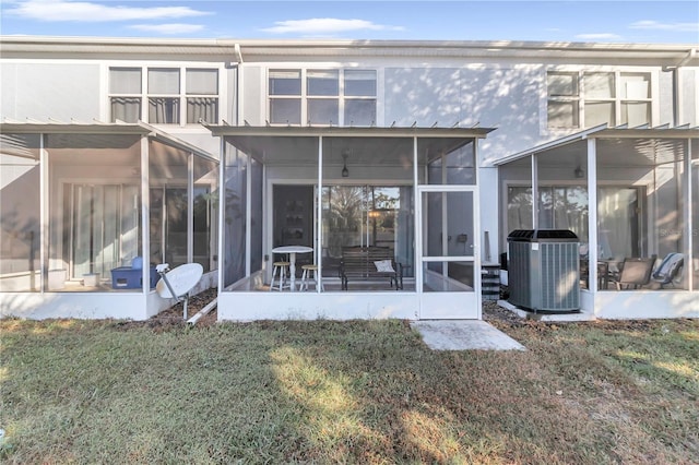 back of property featuring a sunroom, central AC unit, and a lawn